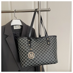 Detail of printed large tote bag with metallic M charm and black leather shoulder straps