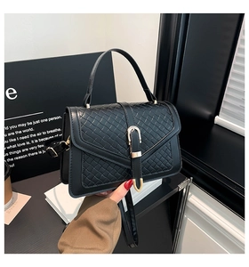 Dettaglio della borsa a tracolla nera con patta intrecciata e fibbia dorata a forma di U