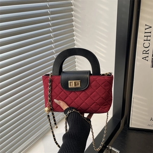 Elegant burgundy quilted chain bag with black top handle and golden ball charm detail