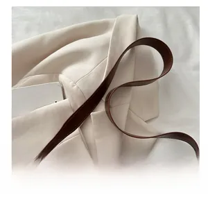 Détail de la bandoulière en cuir marron avec accessoire décoratif en perle de bois