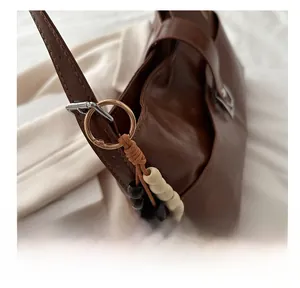 Détail du sac en cuir marron avec boucle dorée et perles décoratives en bois