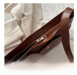 Détail d'un sac en cuir marron avec fermeture éclair fluide et boucle magnétique en métal