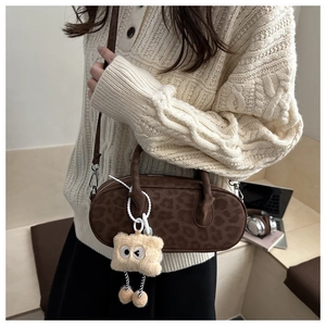 Detail of leopard print baguette bag with plush charm and leather shoulder strap