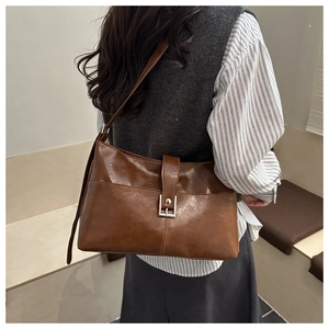 Détail d'un sac cabas en cuir marron avec finition brillante et boucle métallique