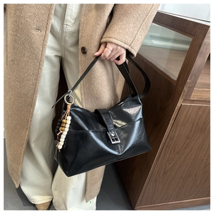 Détail d'un sac hobo en cuir noir brillant orné d'un pendentif ethnique perlé coloré