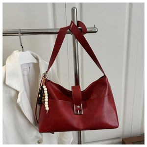 Détail du sac hobo en similicuir rouge avec breloque en bois et boucle métallique