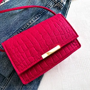 Dettaglio borsa rosso rosa con motivo a coccodrillo e chiusura in metallo dorato