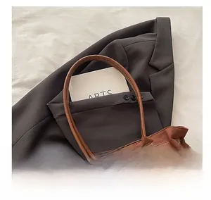 Detail of dark brown frosted suede tote bag featuring colorful beaded charm on blazer