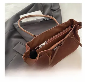 Detail of the suede tote bag showing a smooth silver zipper and interior compartment