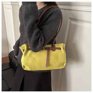 Detail view of the yellow suede handbag showing the shoulder strap and contrast buckle