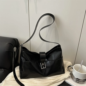 Sac cabas en cuir noir brillant avec boucle argentée dans un décor minimaliste