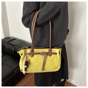 Detail of yellow suede handbag featuring brown leather straps and wooden bead charms