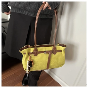 Detail view of mustard yellow suede tote bag featuring brown straps and wooden bead tassel