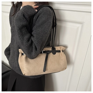 Detail view of the beige suede texture and black leather strap with a metal buckle