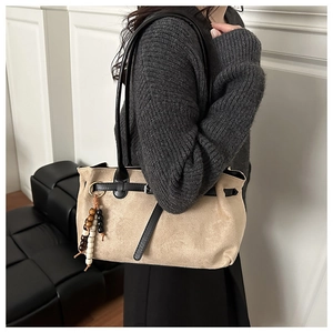 Detail shot of matte suede shoulder bag with chic wooden bead charm and black strap