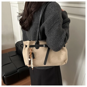 Vintage beige suede shoulder bag featuring a stylish wooden bead charm and black strap