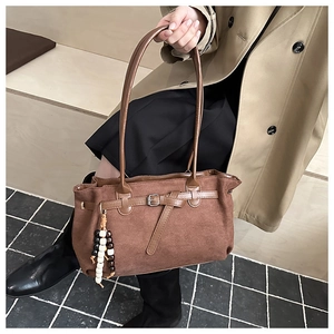 Brown frosted suede handbag featuring minimalist strap detail and wooden bead pendant