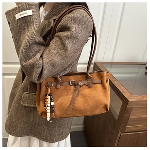 Detail of caramel suede shoulder bag with thin leather strap and wooden bead tassel