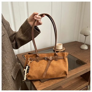 Detailed shot of brown matte suede handbag with decorative buckle and beaded charm accessory