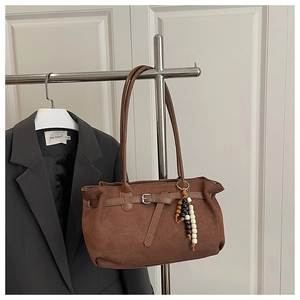 Detailed view of brown matte suede tote bag with stylish wooden bead accessory charm