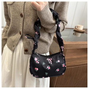 Détail du sac baguette noir avec motif rose rose et poignée froncée élégante