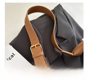 Detail view of adjustable brown faux leather shoulder strap with gold metal buckle