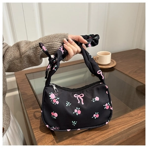 Détail du sac épaule en nylon noir avec imprimés roses roses et nœuds et poignée nouée