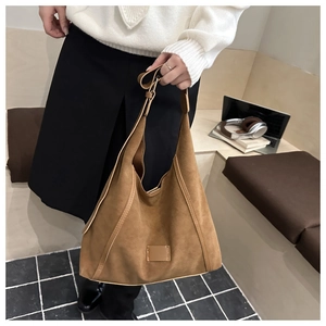 Detailed top view of a large brown suede hobo tote bag placed on checkered tiles