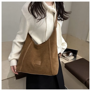 Brown matte suede tote bag shown on shoulder in a professional office setting