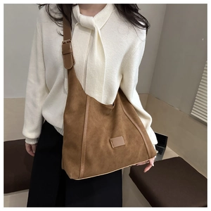 Detail view of brown matte leather tote bag with adjustable shoulder strap and metal hardware