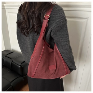 Detailed view of dark red suede hobo bag with vintage texture and gold buckle detail
