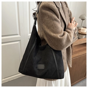 Detail of black large hobo bag with leather trim and adjustable shoulder strap on model