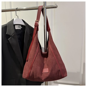 Macro view of burgundy suede tote bag with leather straps and metallic buckle detail