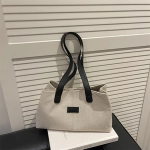 Chic beige canvas tote bag with black straps and minimalist leather patch details