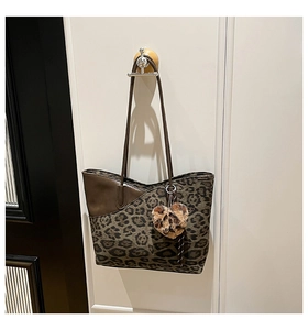 Detail van luipaardprint tote bag met hartjeshanger aan een vintage witte muurhaak