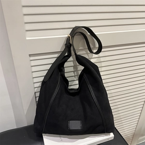 Minimalist black tote bag with irregular silhouette and leather shoulder strap