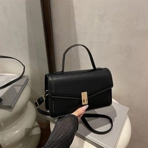 Minimalist black faux leather handbag with gold metal lock and adjustable shoulder strap