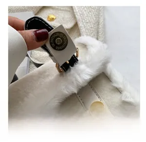Close-up of golden magnetic snap button on off-white crossbody bag with faux fur trim