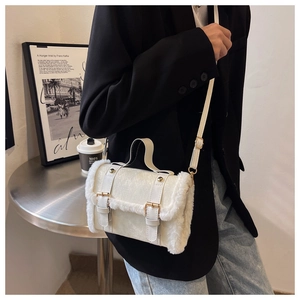 Detail of cream crossbody bag with faux fur trim and gold buckles on a chic background