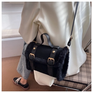 Detail of a chic black faux fur handbag with gold buckles and a leather shoulder strap