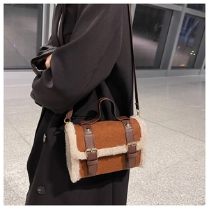Brown suede crossbody bag with cream faux fur trim and leather buckles in a modern interior