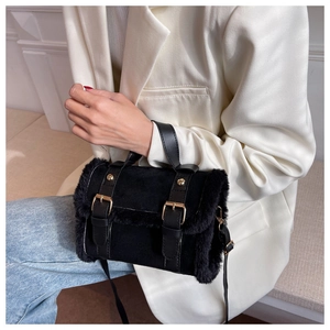 Close-up of black suede handbag with faux fur trim and gold metal buckles detail