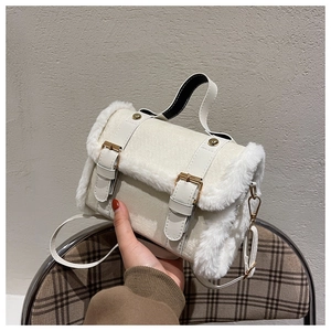 Close-up of white leather crossbody bag with plush faux fur trim and gold buckle details