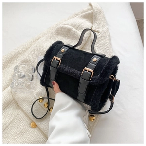Detail of black plush handbag featuring faux fur texture and golden metal hardware