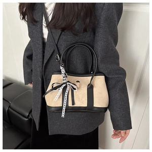 Detail of beige suede handbag with black leather trim and lace-patterned silk scarf decor