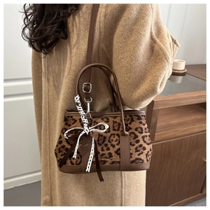 Detail of leopard print handbag with ribbon bow and faux leather strap on coat