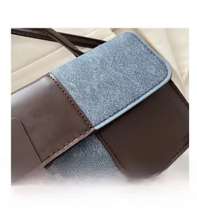 Detailed view of color-block square bag with brown leather and blue textured fabric