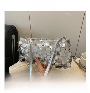 Detail shot of shimmering silver oversized sequins on a chic metallic underarm bag
