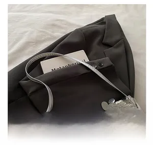 Detail of silver sequin shoulder bag showing metallic texture against a grey blazer