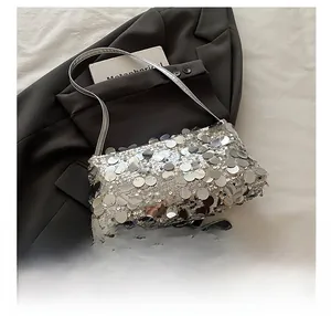 Close-up of silver sequin shoulder bag with metallic mirror finish on gray blazer